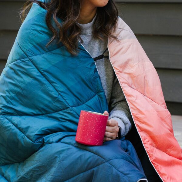 Model shown using the recycled nanoloft puffy blanket with cape clip, which allows wearer to use the blanket hands-free.