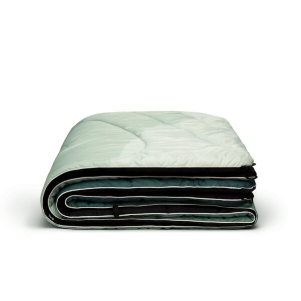 The eco-friendly original puffy blanket in cascade fade green has a multi-colored green front, dark green back, and white binding.