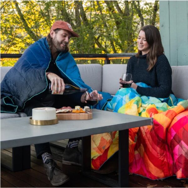 Couple sitting on outdoor patio with Rumpl recycled down alternative puffy blankets