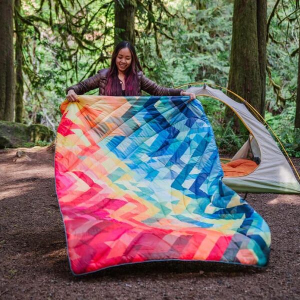 Woman camping shaking out recycled down alternative puffy blanket