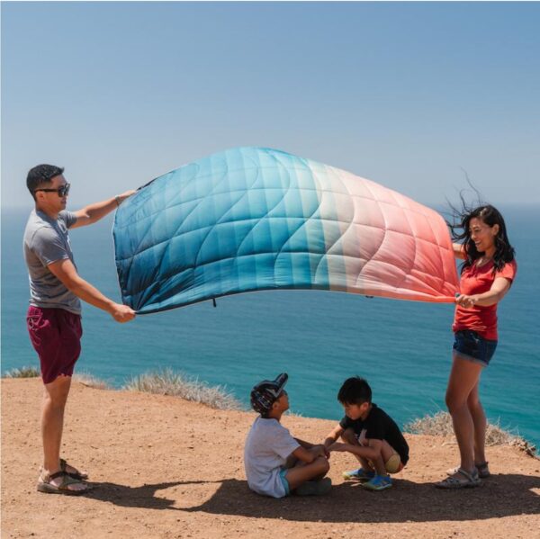 Family at beach with Patina Pixel recycled, down-alternative blanket from Rumpl