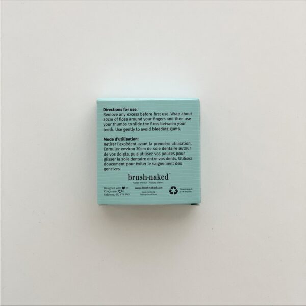 Brush Naked eco-friendly dental floss is made from corn, is biodegradable and vegan, and comes in recyclable cardboard packaging. Back of packaging is shown with directions for use.