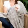 Woman wrapped in grey eco-friendly organic cotton knit throw blanket