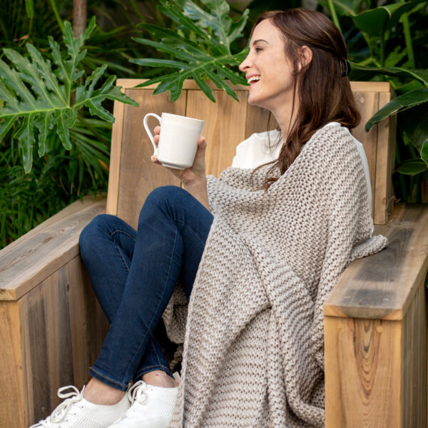 Woman with organic cotton grey throw blanket for low waste living