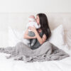 Woman and baby in bed with eco-friendly grey throw blanket from Zestt Organics
