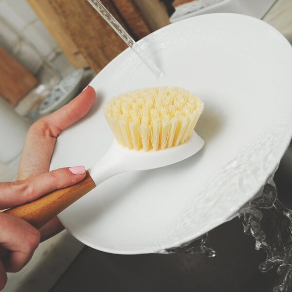Eco friendly recycled plastic and bamboo dish cleaning brush from Full Circle cleaning a dish