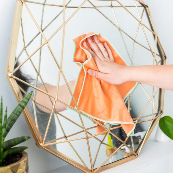 Orange recycled microfiber cleaning cloth on a gold mirror for eco friendly cleaning products