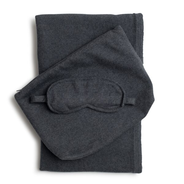 The Organic Cotton Travel Set by Zestt Organics, shown in dark gray, comes with a knit throw, eye mask, and carrying pouch.
