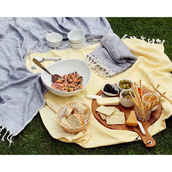 Photo shows an assortment of picnic foods sitting on top of a yellow and black earth-friendly Hilana blankets made from regenerated cotton.