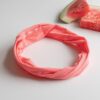 A Kooshoo twist headband shown in sugar coral; made from organic cotton and locally dyed, cut, and sewn in a fair trade certified Los Angeles facility