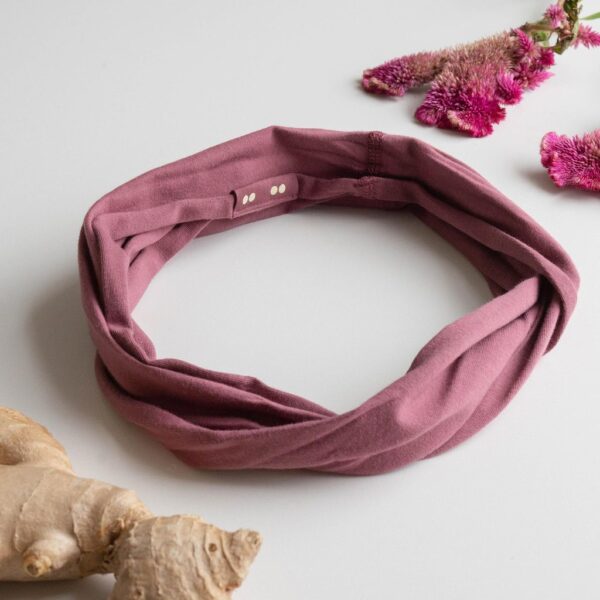A Kooshoo twist headband shown in wild ginger; made from organic cotton and locally dyed, cut, and sewn in a fair trade certified Los Angeles facility