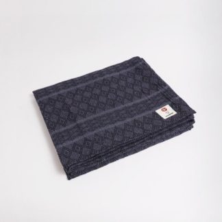 The Peruvian recycled cotton blanket by Manduka features a beautiful gray diamond pattern and is made from mostly recycled materials.