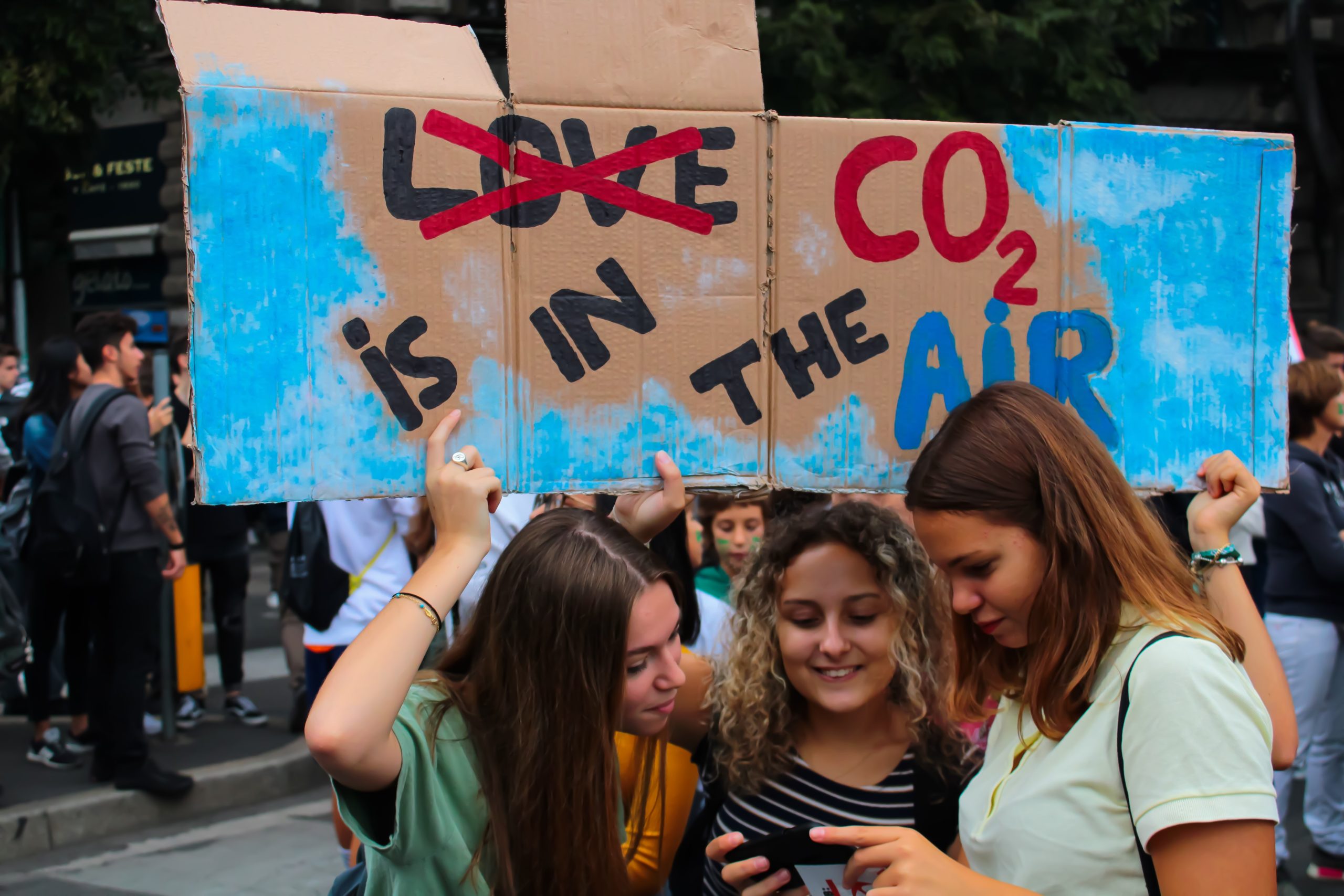 Young girls with Love CO2 is in the air protest sign