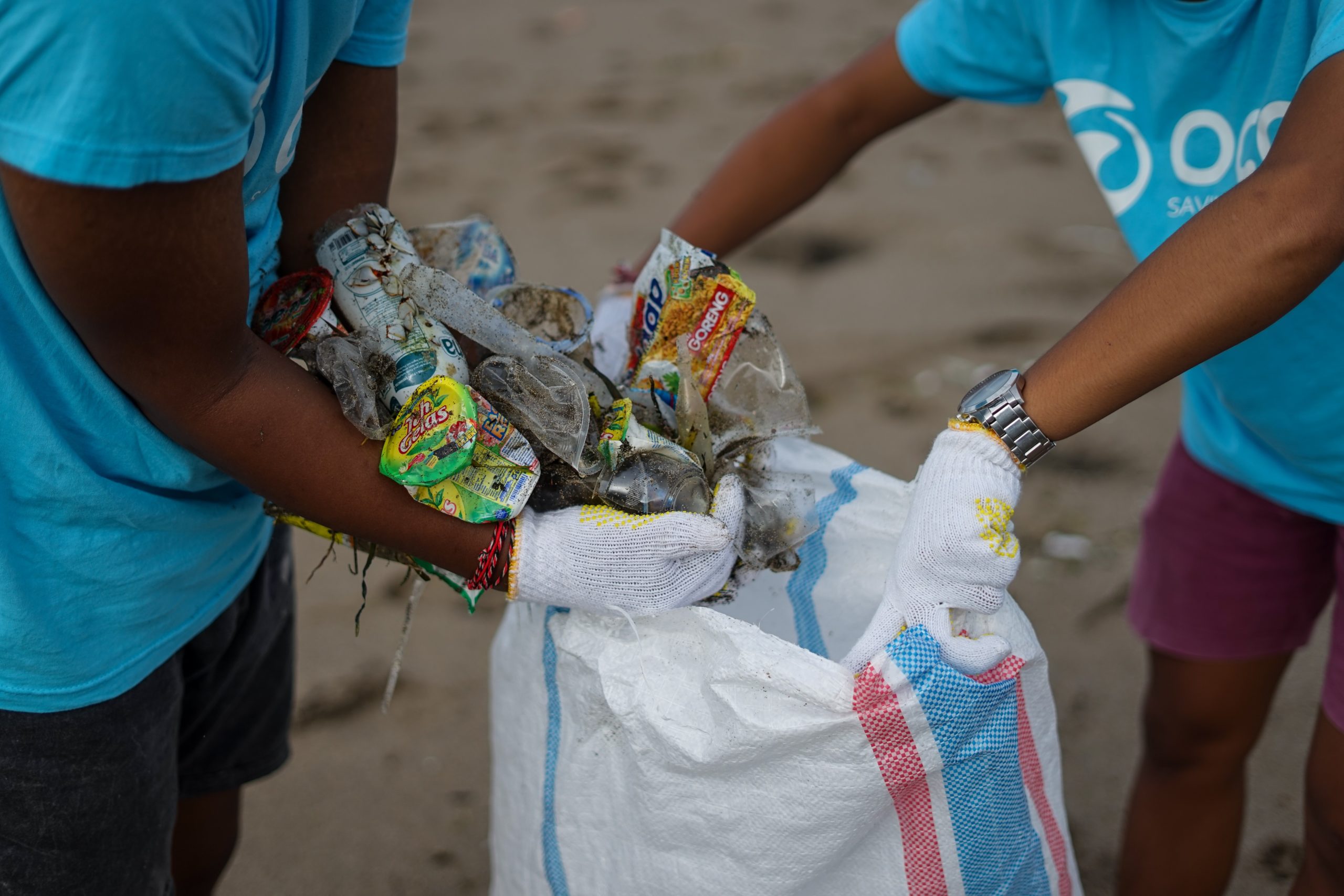 Hands of two youth doing beach clean up