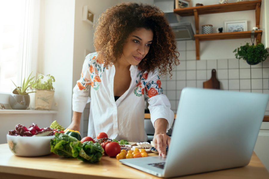 Woman with food looking at computer for ways to reduce food waste at Thanksgiving blog