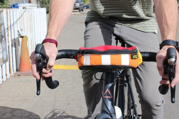 Close up showing that the Hipster hip pack by Green Guru can be attached to the handlebars of a bike, and then can be taken off the bike as needed and worn as a hip pack.