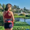 Female model, taking a break from her run, is wearing the Tripster eco-friendly hip pack by Green Guru around her waist.
