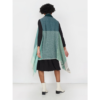 The eco-friendly Cape Infinity by Fifth Origins, shown here on a model in aurora green, is woven in a color block pattern and is made by women artisans in India.