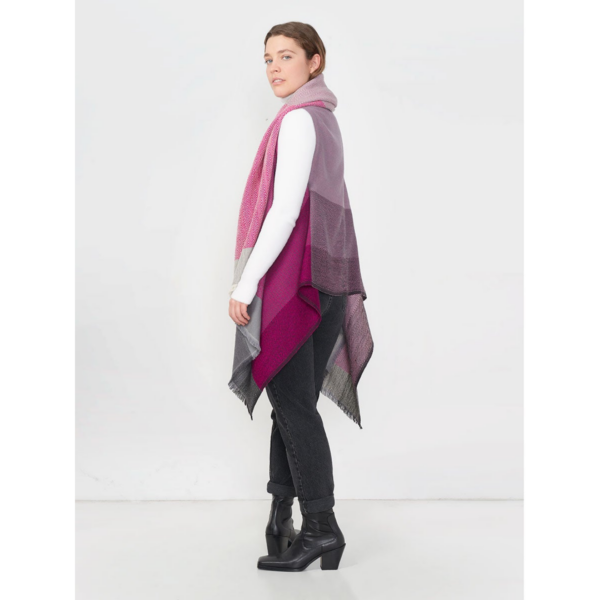 The eco-friendly Cape Infinity by Fifth Origins, shown here on a model in flamingo pink, is woven in a color block pattern and is made by women artisans in India.