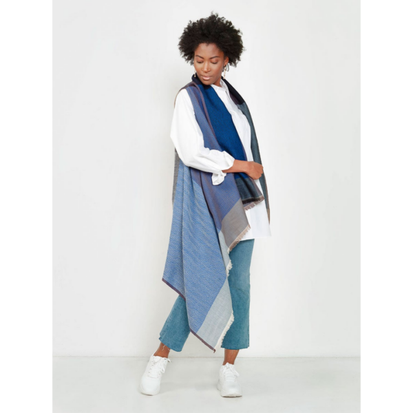 The Cape Infinity by Fifth Origins, shown here on a model in sky blue, is woven in a color block pattern and is made by women artisans in India.