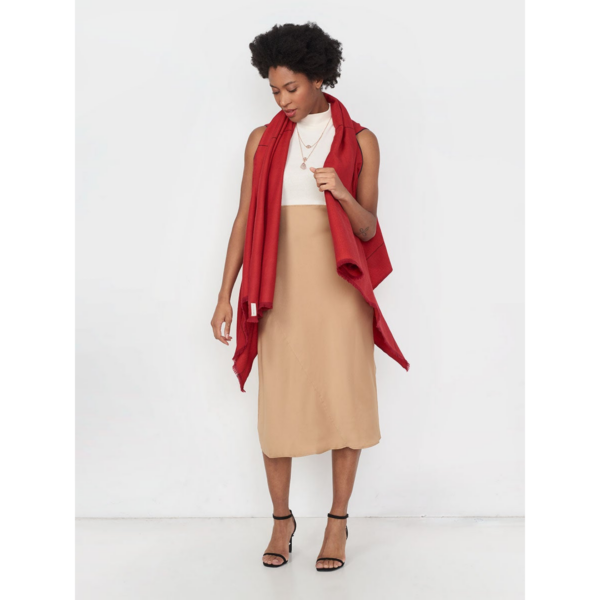 The sustainable Artisanal Cape Infinity Lite, modeled here in rose red, is made from 100% organic Himalayan wool and is woven by women artisans.