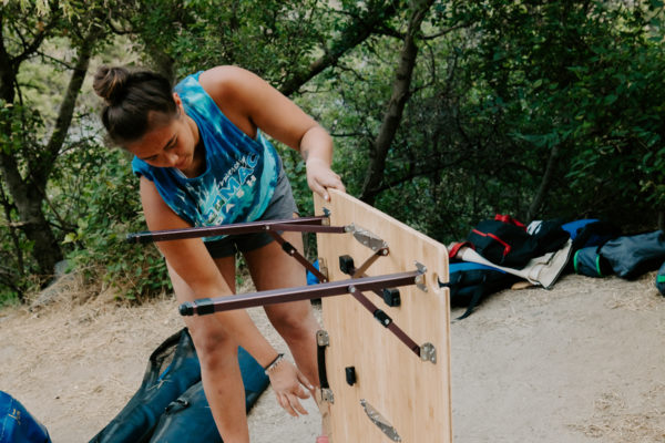 Woman picking up portable, camping table made from sustainable bamboo