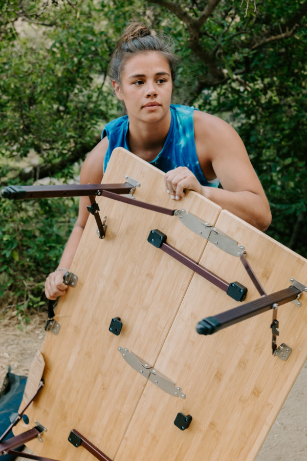 Woman picking up portable, camping table made from sustainable bamboo