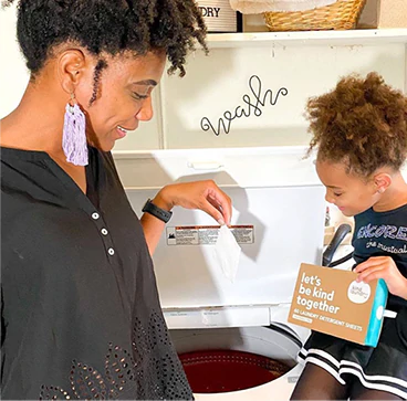 Woman and her child putting eco-friendly laundry detergent sheet in the top-load washer