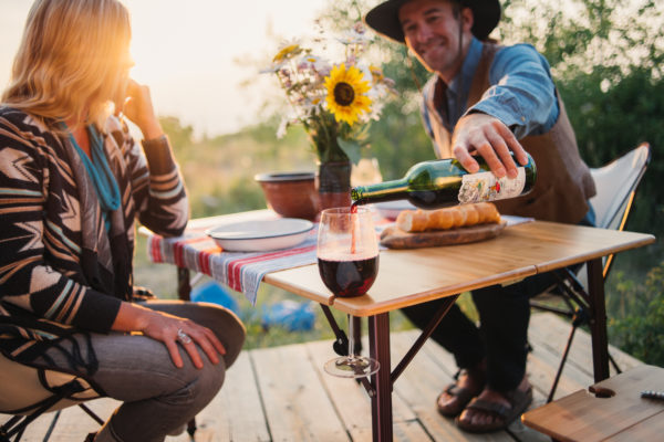 Couple pouring wine for picnic on portable bamboo travel table