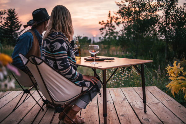 Couple drinking wine at sunset on portable bamboo travel table