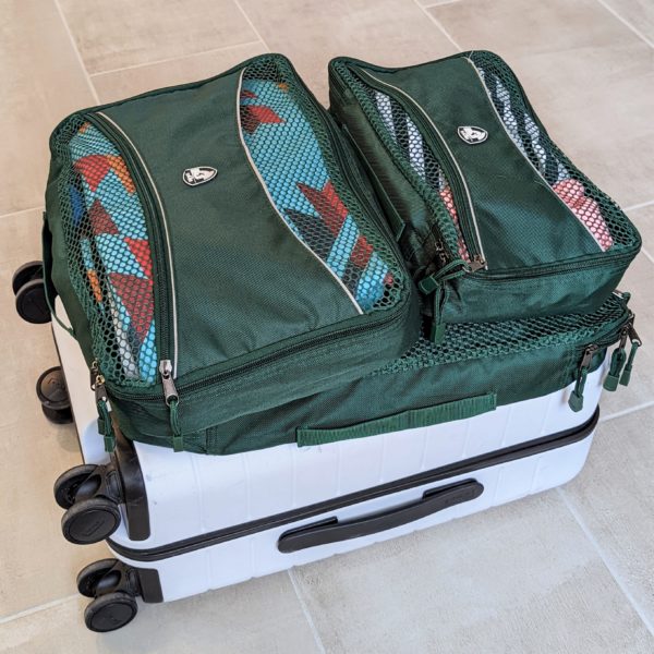 Set of green packing cubes on a carry on suitcase for sustainable travel