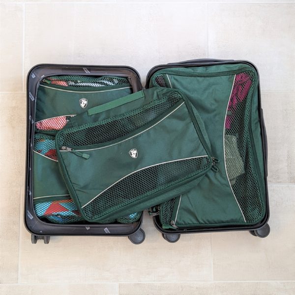 Overhead view of recycled, green packing cubes in carry on suitcase for sustainable travel