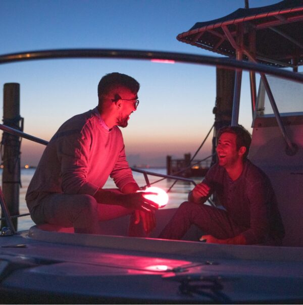 Two guys with Explore solar powered light and speaker by the water