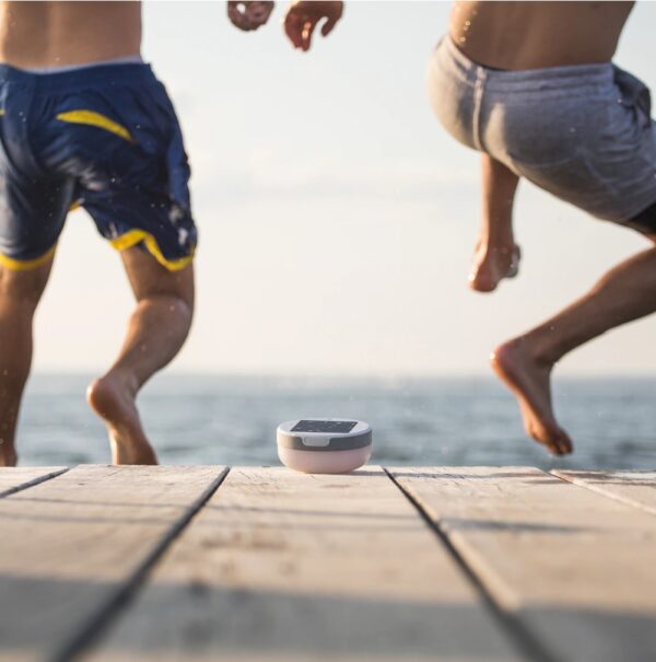 Guys jumping off lake dock near solar powered light and speaker