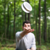Guy tossing hand-sized Explore solar powered light and speaker for outdoor travel
