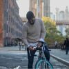 Man in city putting solar powered headlight onto bike for sustainable bike gear