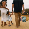 Photo of a family walking to the beach with their young child, picnic basket and Nomadix sustainable beach towels in hand.