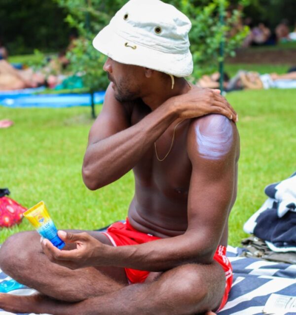 Man putting on reef-safe, non-toxic sunscreen in 3oz travel size for outdoor picnic