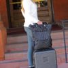 Model is shown arriving at her hotel with her stylish and earth-friendly Meridian luggage by Sherpani. Luggage is shown in black with Sherpani flower logo on the front.