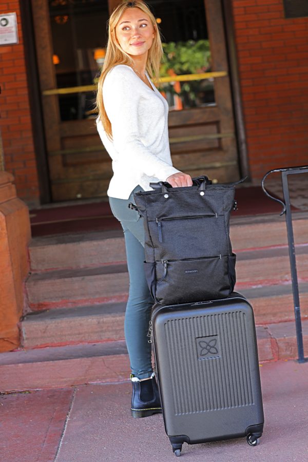 Model is shown arriving at her hotel with her stylish and earth-friendly Meridian luggage by Sherpani. Luggage is shown in black with Sherpani flower logo on the front.