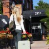 Model is shown walking toward her hotel on the sidewalk, pulling her Meridian luggage in sage, by Sherpani. This luggage is sturdy, lightweight, and has an anti-crush exterior.