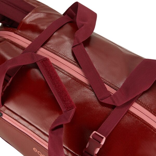 The migrate duffel bag by Eagle Creek, shown here in burnt berry, is a 40 liter duffel bag with dark red straps that velcro and is made from 100% recycled materials.