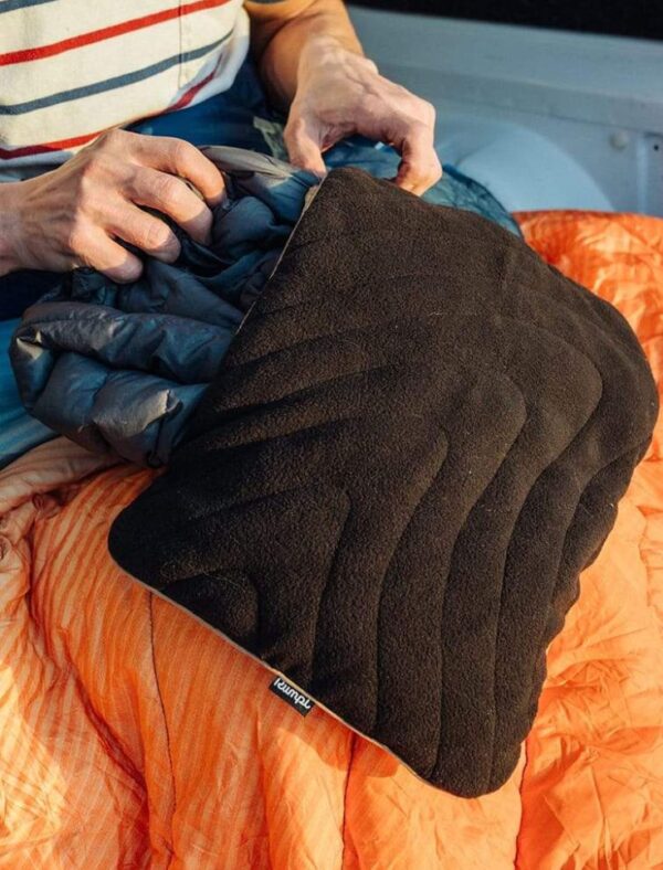 Eco-friendly camping with person using black stuffable travel pillowcase from Rumpl.