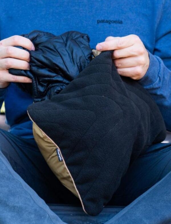 Person's hands stuffing Rumpl, recycled travel pillowcase in navy