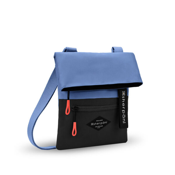 The sustainably-made Sherpani Pica crossbody bag is shown here in Pacific Blue, which is a color-blocked blue and black bag with bright red zipper pulls.