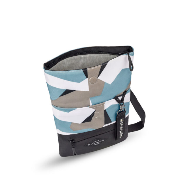 The Sherpani Pica crossbody bag, made from 100% recycled materials, is shown here in a geometric camo color on top and a black colorblock on the bottom. It has a zippered fold-over pocket and includes a detachable keychain.