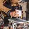 Person putting camping coffee on portable, aluminum Canyon side table