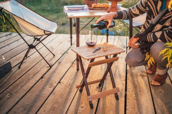 Person pouring wine on eco-friendly bamboo side table for backyard and camping