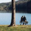 Couple carrying sustainable wood, foldable chairs near lake