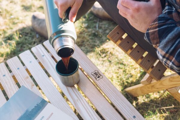 Pouring camp coffee over portable, wood table made in USA